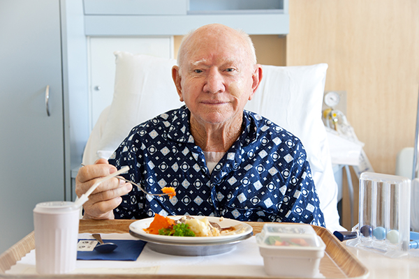 senior man eating in hospital bed