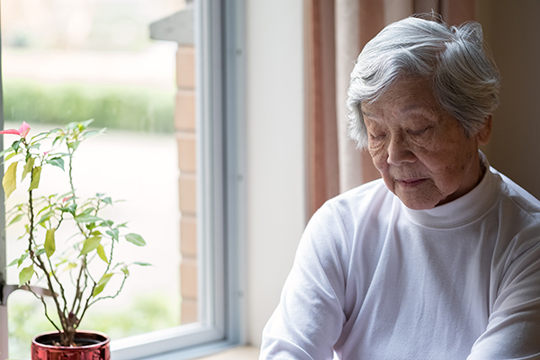 lonely-senior-woman-by-window Serious senior woman in her 90s, with eyes closed.