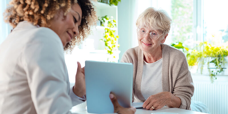 Smiling senior woman talking with advisor, sitting at the table.