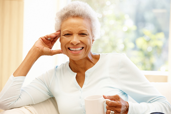 Senior woman at home drinking hot drink and smiling