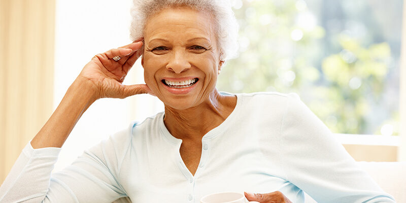 Senior woman at home drinking hot drink and smiling