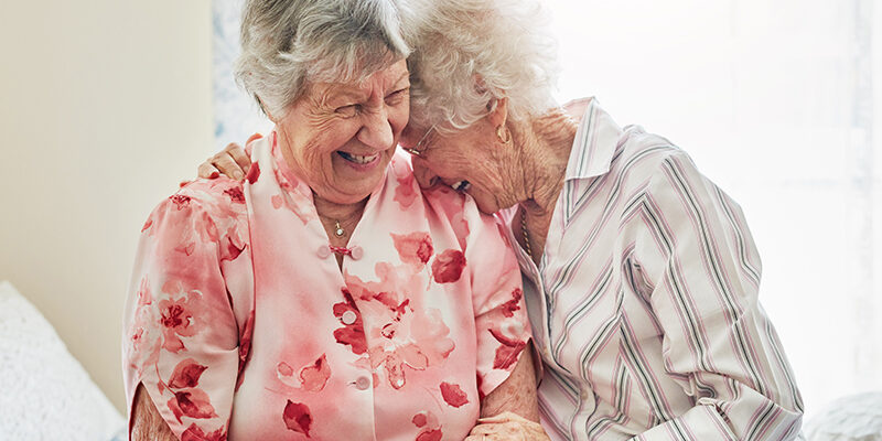 two happy elderly women spending time with each other at home