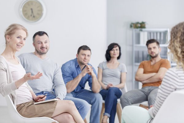 Therapist congratulating woman on progress Therapist in group meeting