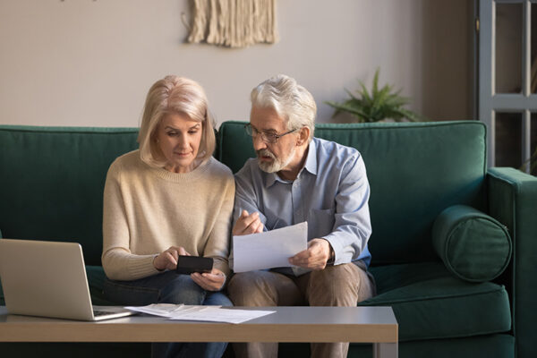 Serious mature couple calculating bills, checking domestic finances Serious mature couple calculating bills to pay, checking domestic finances, middle aged family managing, planning budget, expenses, grey haired man and woman reading bank loan documents at home