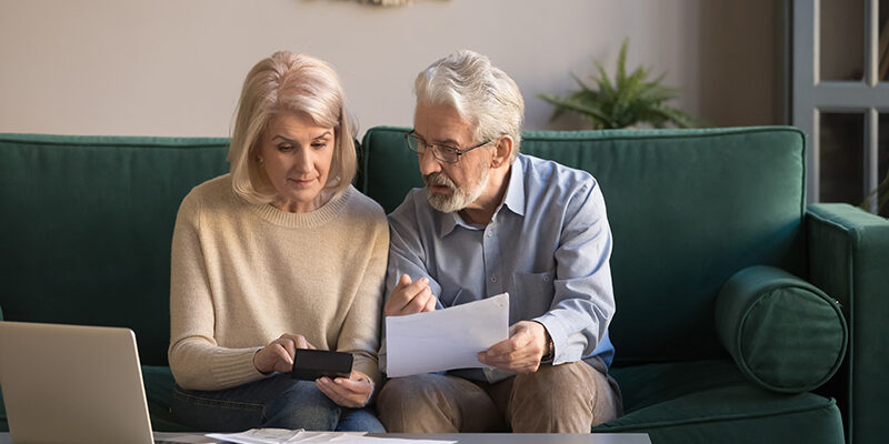 Serious mature couple calculating bills, checking domestic finances Serious mature couple calculating bills to pay, checking domestic finances, middle aged family managing, planning budget, expenses, grey haired man and woman reading bank loan documents at home