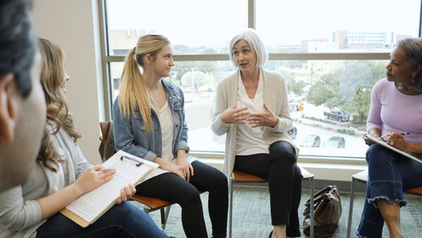 Grandmother explains her position to granddaughter during therapy With a serious look on her face, the teen girl looks at her grandmother during group therapy.