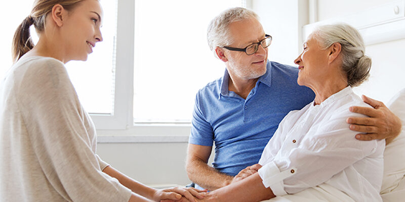 happy family visiting senior woman at hospital caregiver comforting senior couple