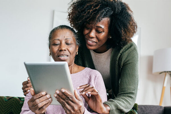 caregiver-showing-senior-lady-something-on-tablet senior lady and adult daughter looking at tablet