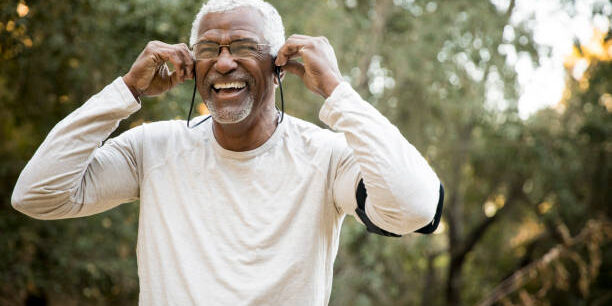 A senior African American Man gets his headphones ready during a workout